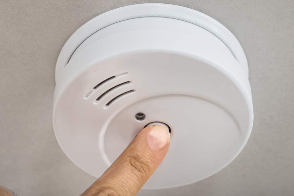 A smoke detector being tested by someone pressing the test button.